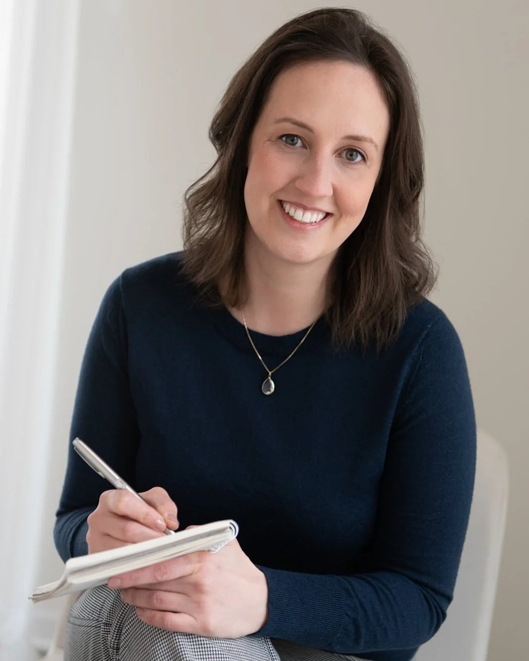 Financial coach for women Annie Hanson holiding notebook and pen and smiling.