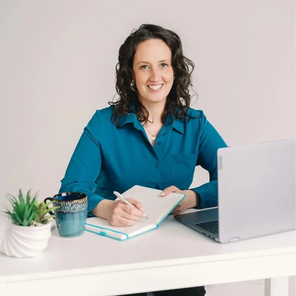 financial coach Annie Hanson at desk with teal notebook and computer