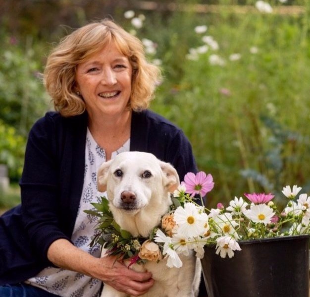 Woman and white dog with bucket of flowers
