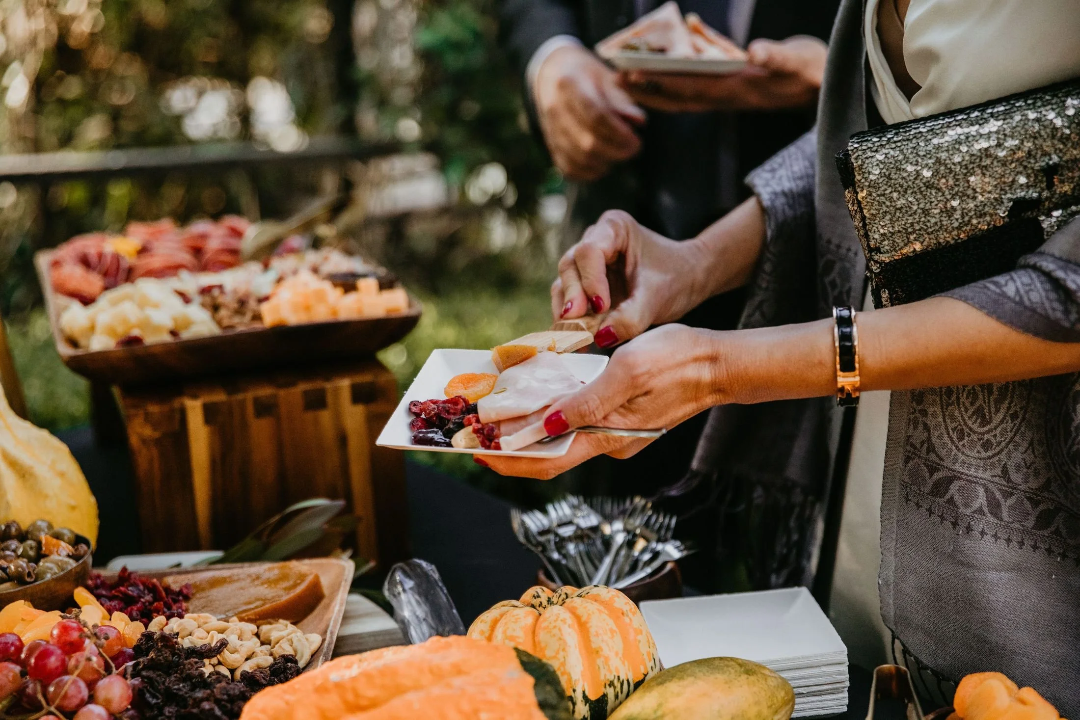 Event guests serving themselves from a catered grazing table with fruit and charcuterie