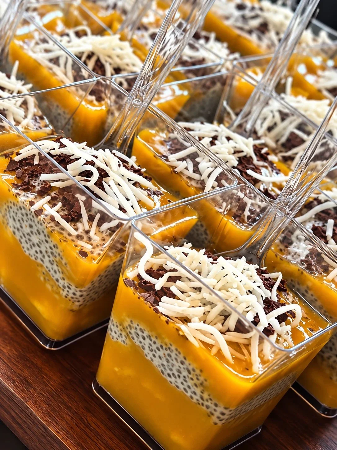 Mango chia pudding cups topped with shaved coconut and chocolate at a Los Angeles office breakfast