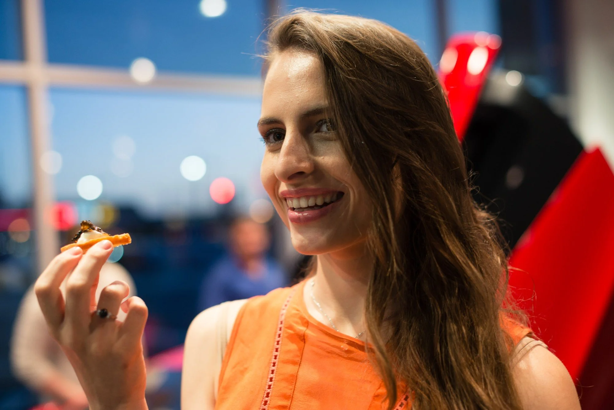 Guest smiling as she enjoys a passed canape during an evening reception
