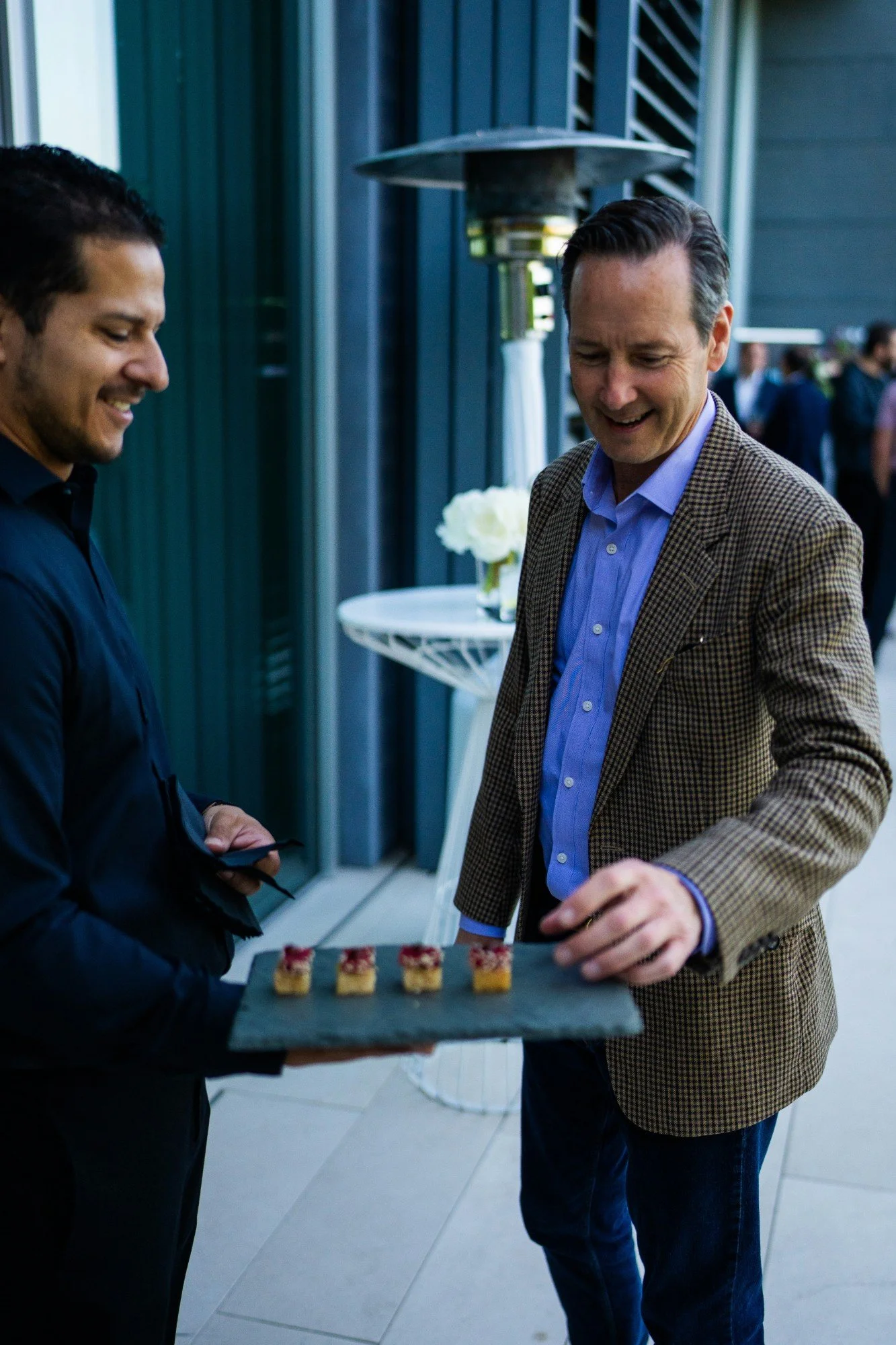 Server discreetly offering a slate tray of canapes to a guest at a reception