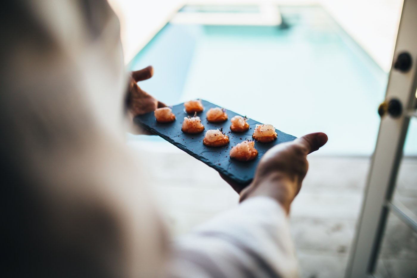 Server presenting canapes on a slate tray, plated with precision to match the setting