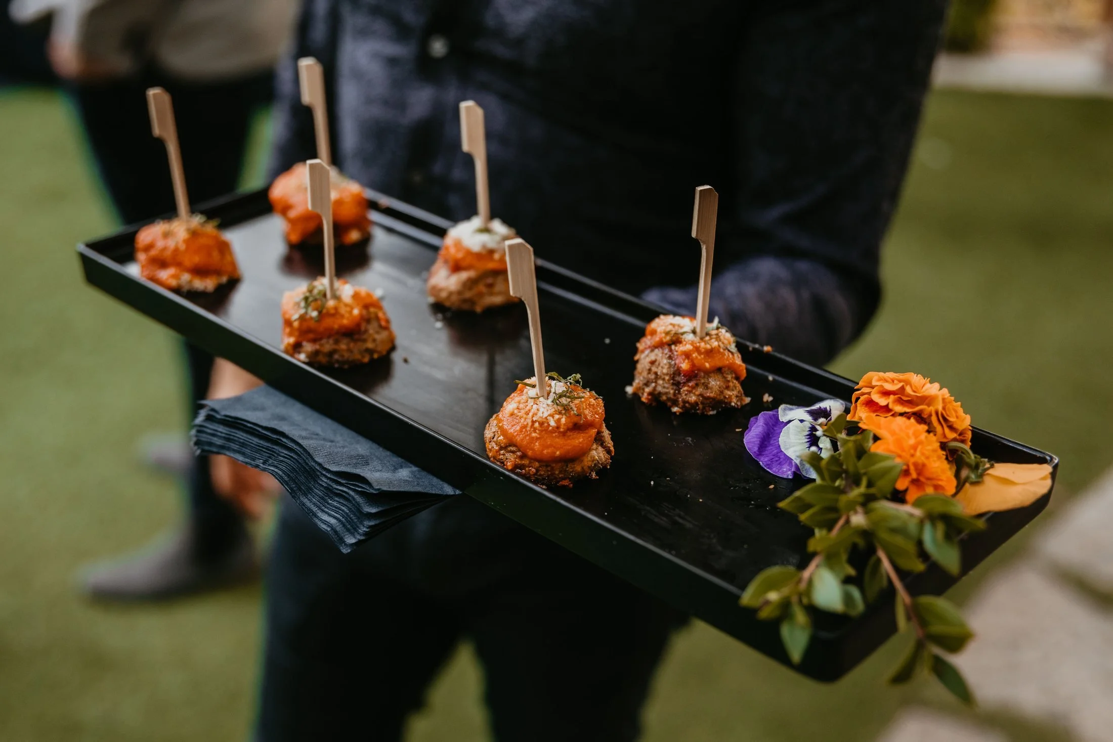 Catering server presenting a tray of passed appetizers at an outdoor event
