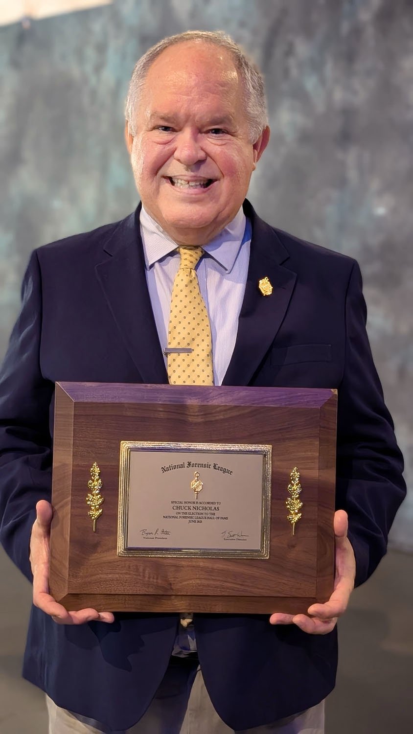 Man, Chuck Nicholas, holding a wooden and brass plaque.