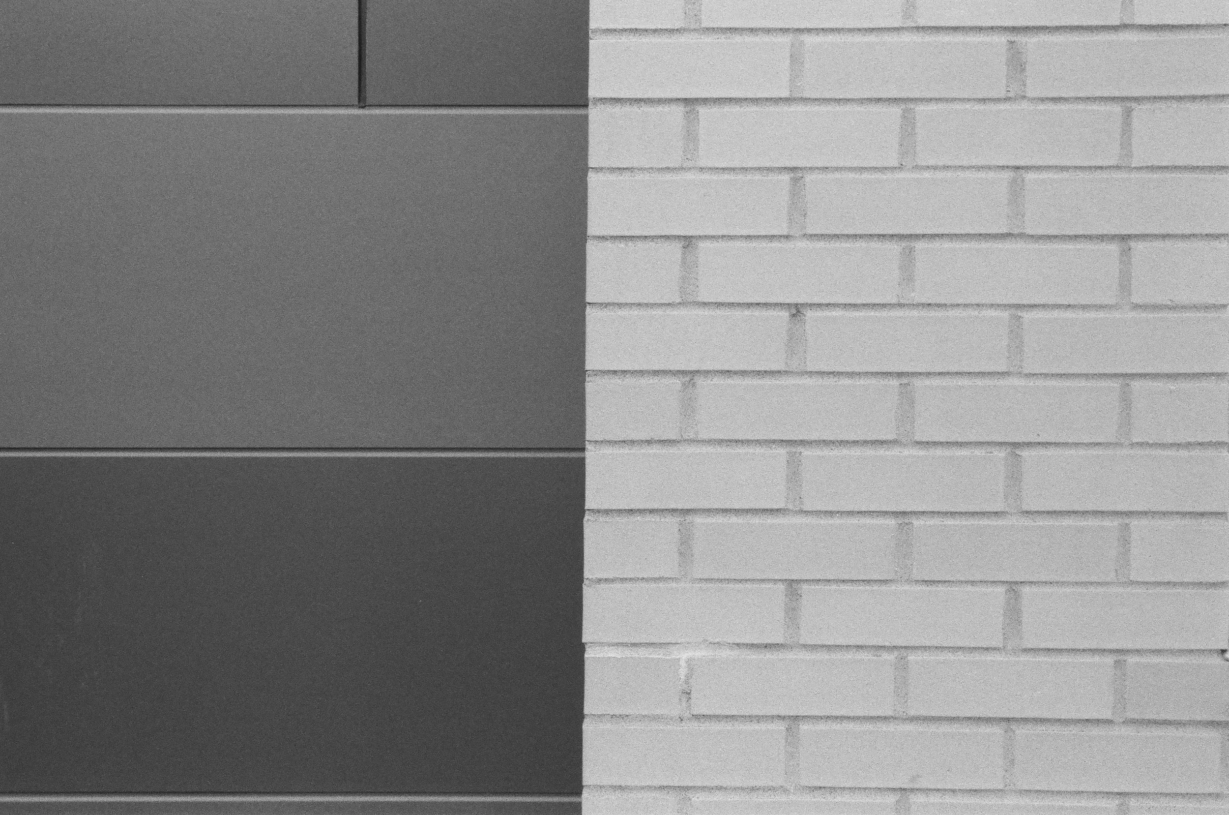 Black and white image of a flat-panel cabinet door on a wall and a white brick wall side by side.