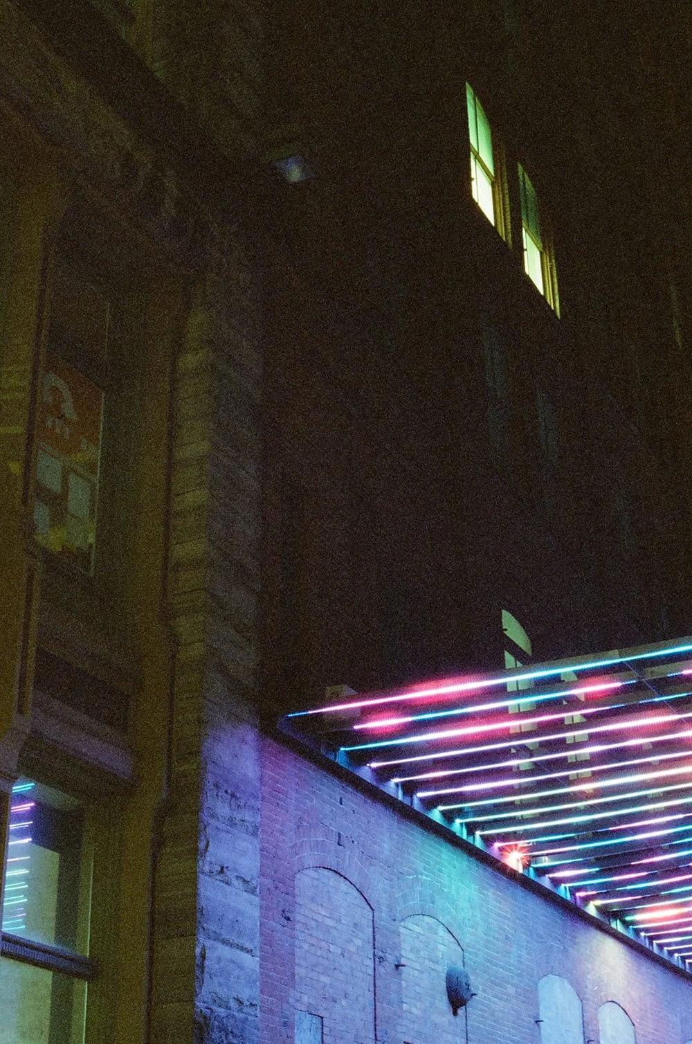 Nighttime scene of a building with illuminated neon-colored lights and lit windows.