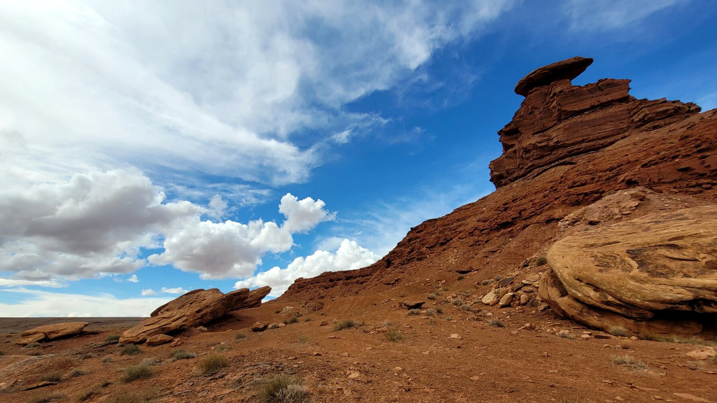 Desert landscape with rock formations and blue sky with clouds.
