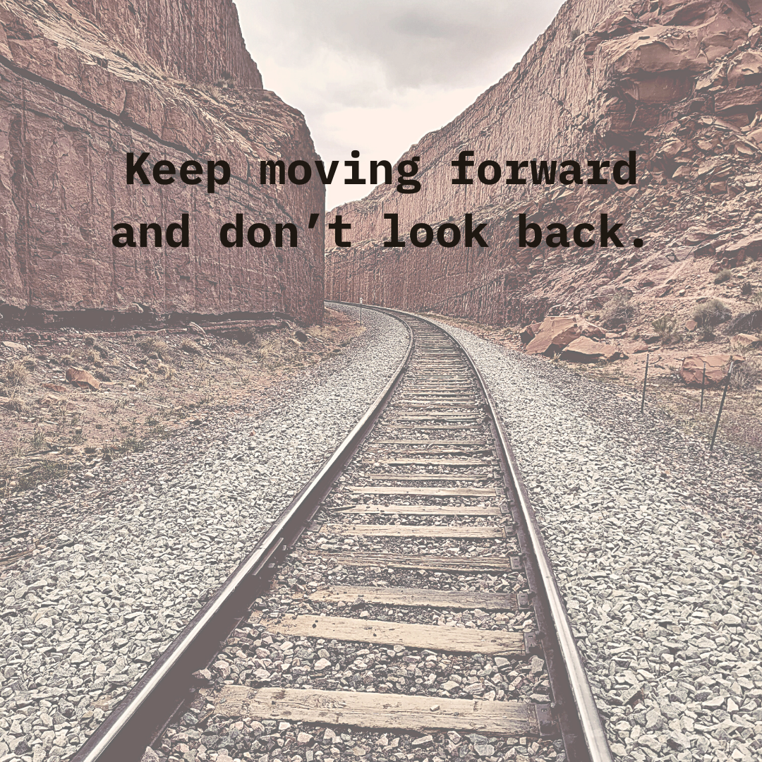 Railroad tracks between rocky cliffs with motivational text "Keep moving forward and don’t look back."