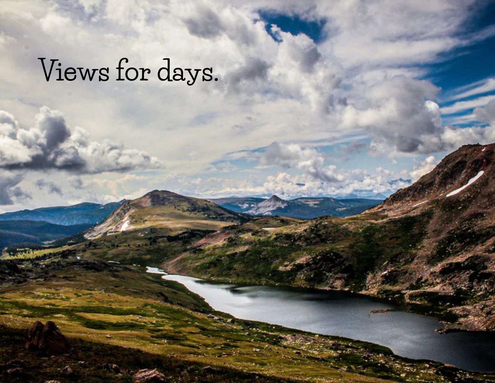 A mountainous landscape with a river flowing through valleys under a partly cloudy sky, with the text "Views for days." overlaid.