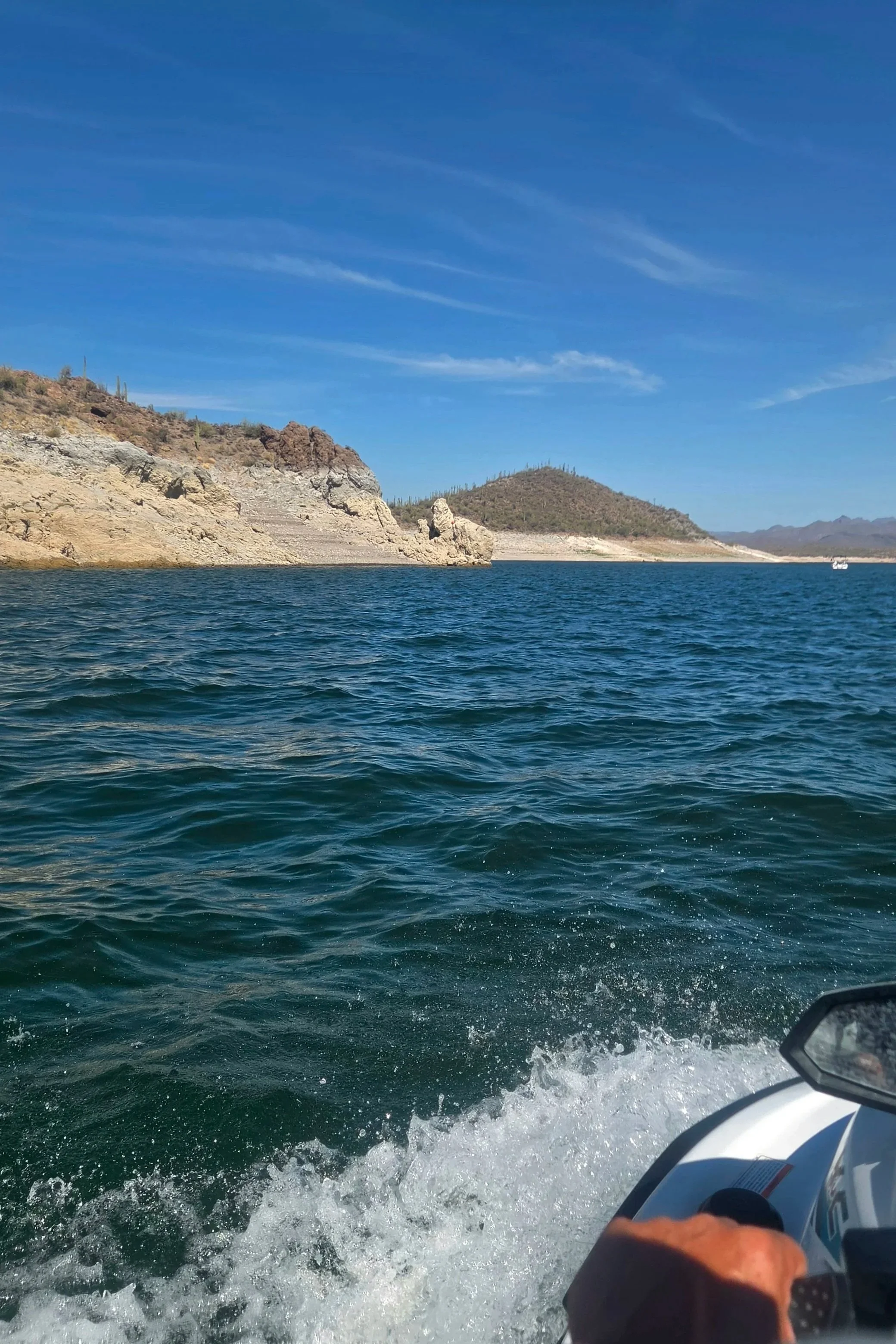 Lake with jet ski and small mountains nearby