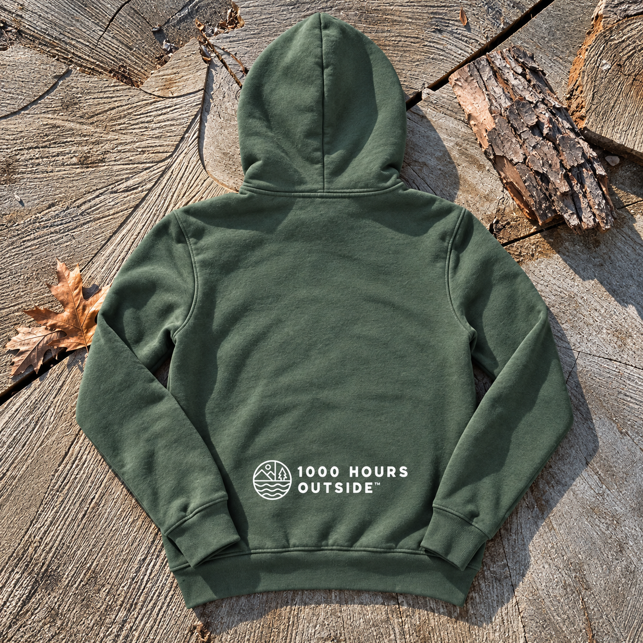 Forest Green Hoodie on Rustic Tree Stump.png