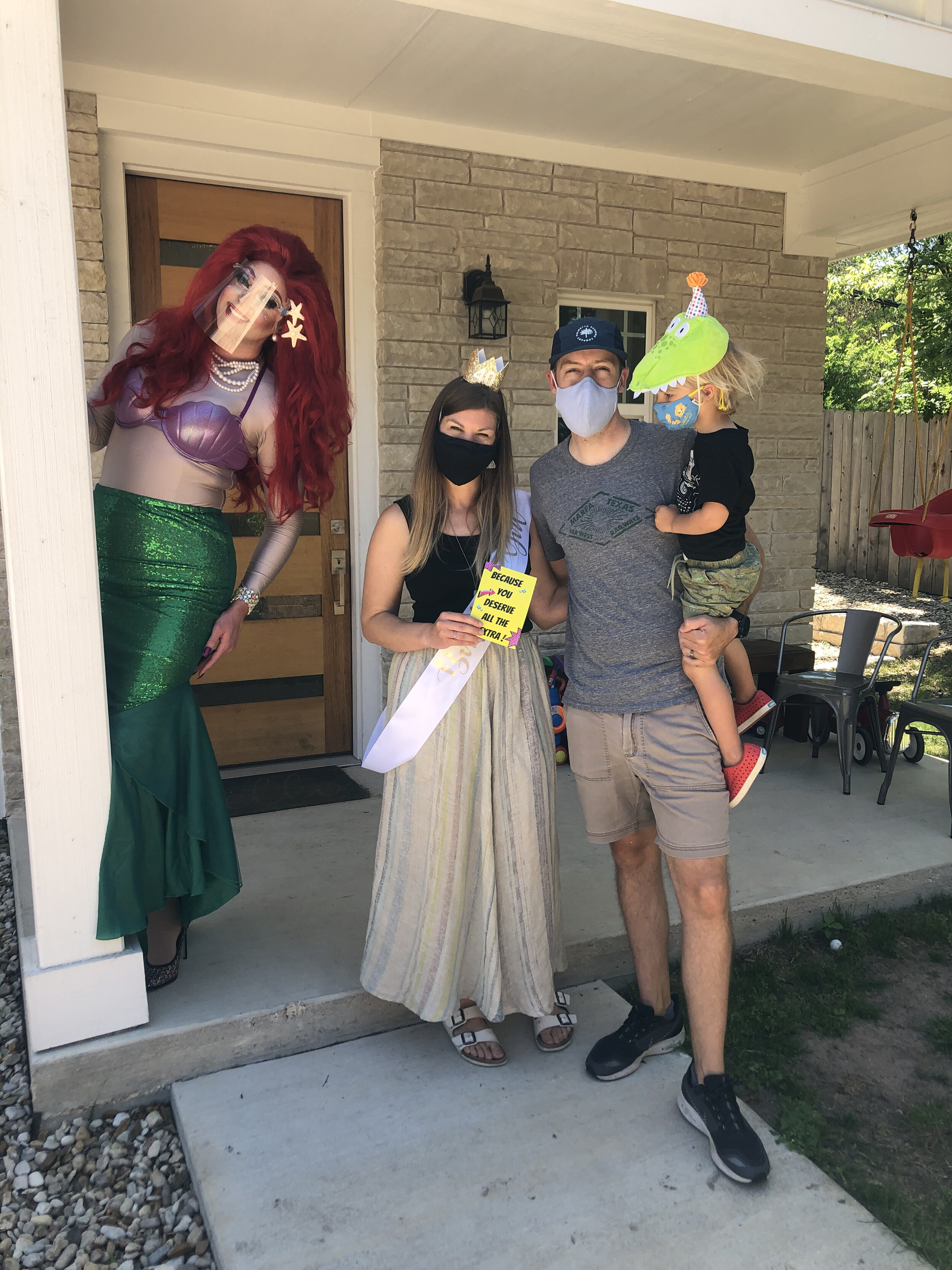 People dressed in costumes and wearing masks standing on a porch, celebrating a special occasion.