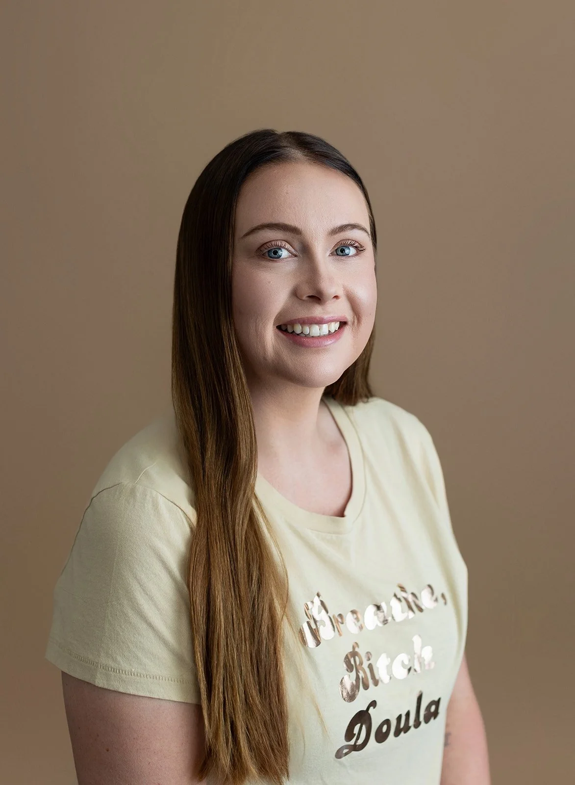 woman with long golden brown hair, blue eyes, and shiny text on shirt