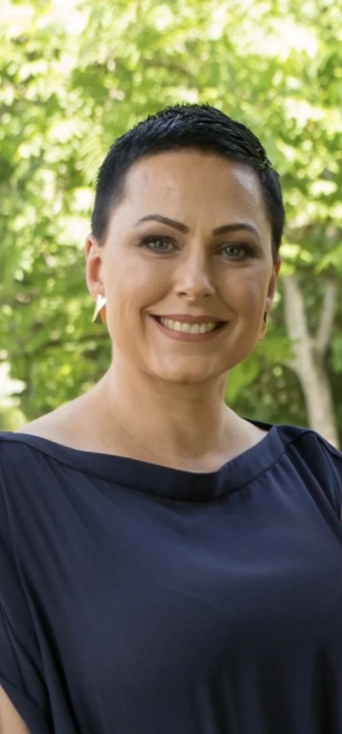 woman with short, dark hair, blue eyes, and gold earrings
