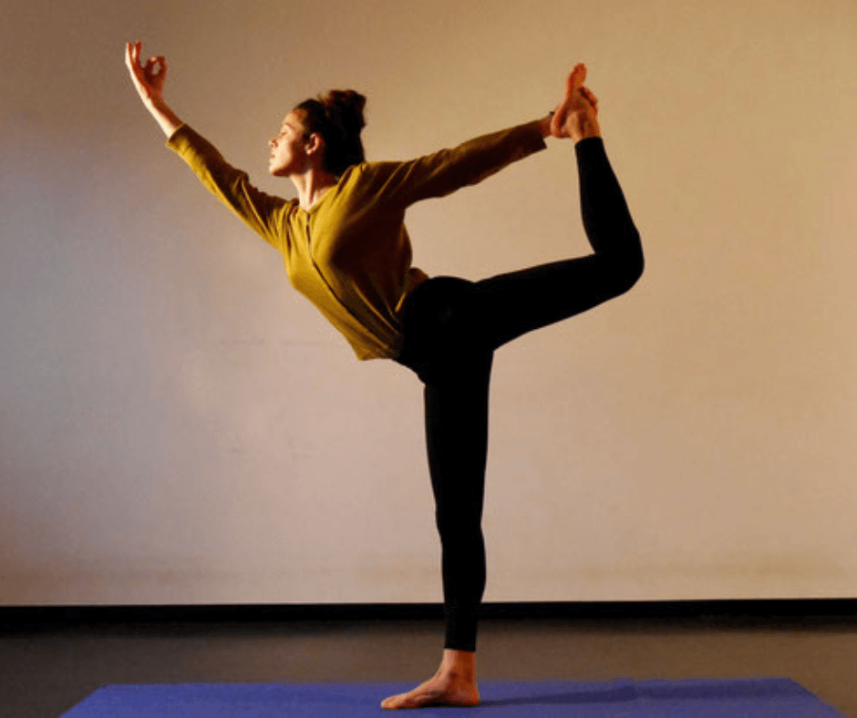 Judith Nagel  in einer Yoga-Pose, bei der sie ein Bein hinter den Rücken hebt und mit den Händen hält.