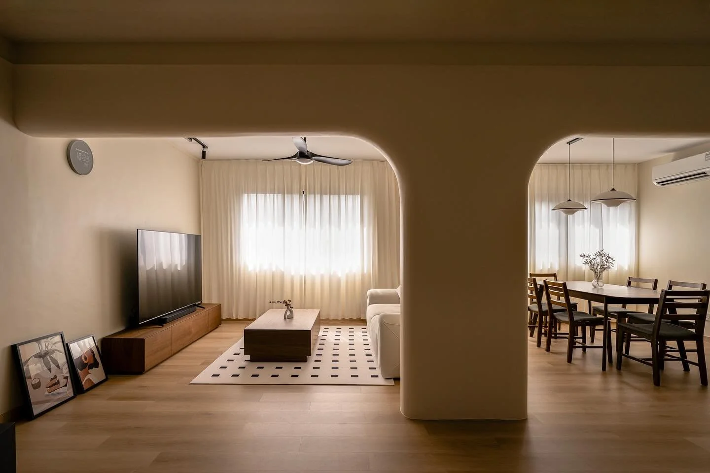 Soft curves, warm wood tones and gentle daylight.

Every element in the house tells a story of calm simplicity. The arched beam softens structure into sculpture, sheer curtains diffuse light into gold, and textures speak quietly of comfort. Dark timb