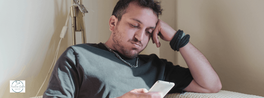 Man on his phone trying to find a therapist that will understand him.
