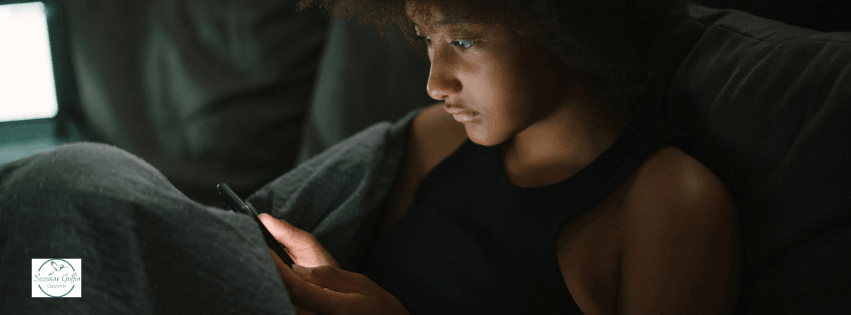 Young black woman looking for a therapist on her phone.