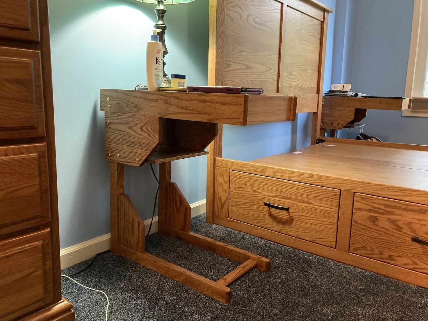 Cantilevered tables in on either side of Amish built bed after it was repositioned. Note the lower shelf for charging computers, phones etc.