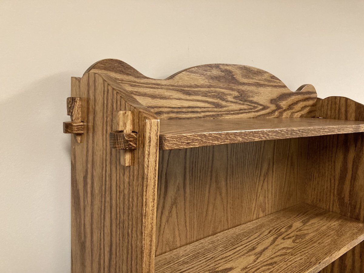 Through tenons with wedge detail. Top and bottom shelf are pinned while three middle shelves float and can be adjusted.