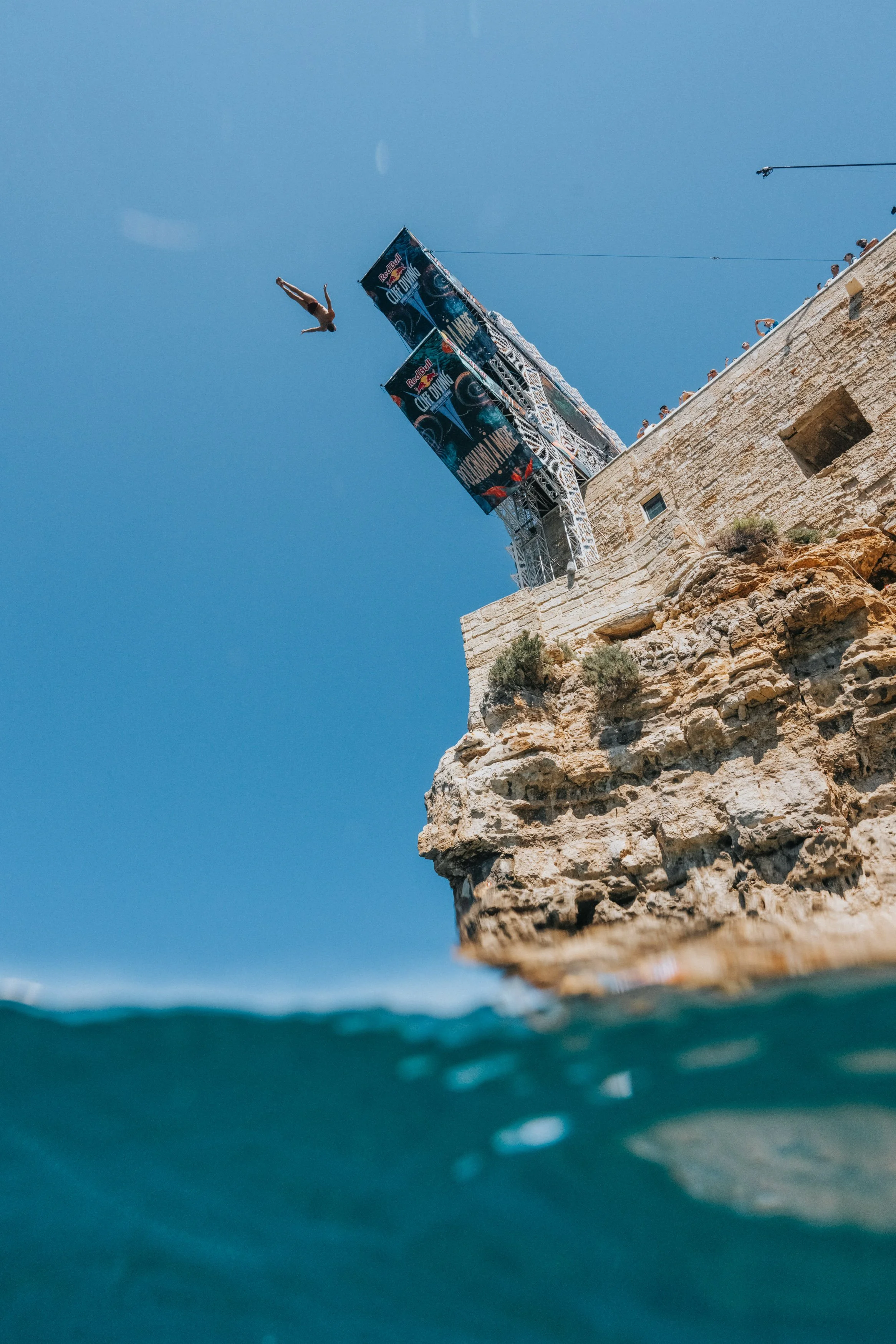A person diving from a cliff into the water during a Red Bull cliff diving event.