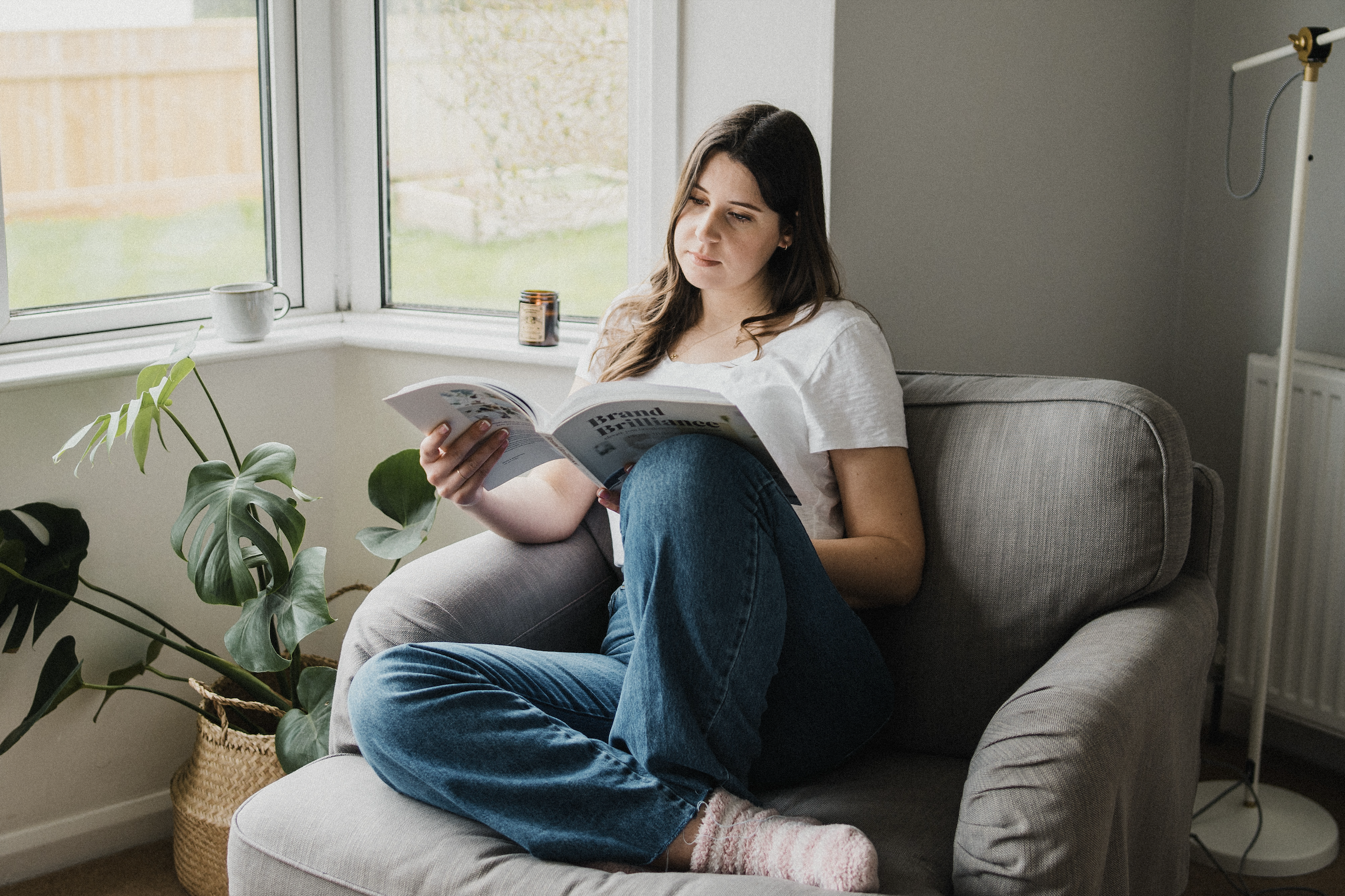 Business owner researching brand naming ideas while reading in a cozy armchair