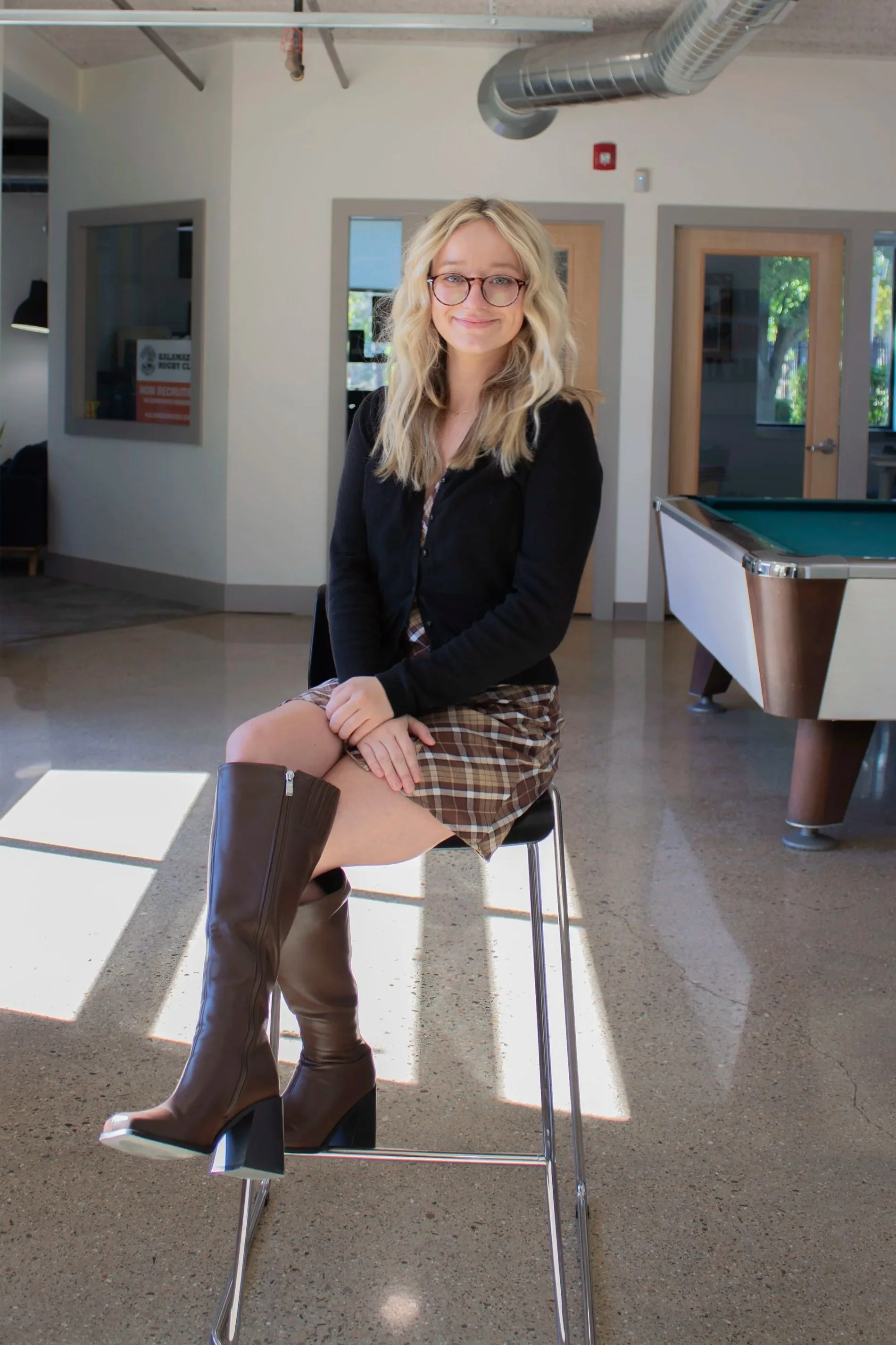 Mara Wilder, Marketing Director at Kalamazoo Commercial Real Estate sits in a chair.