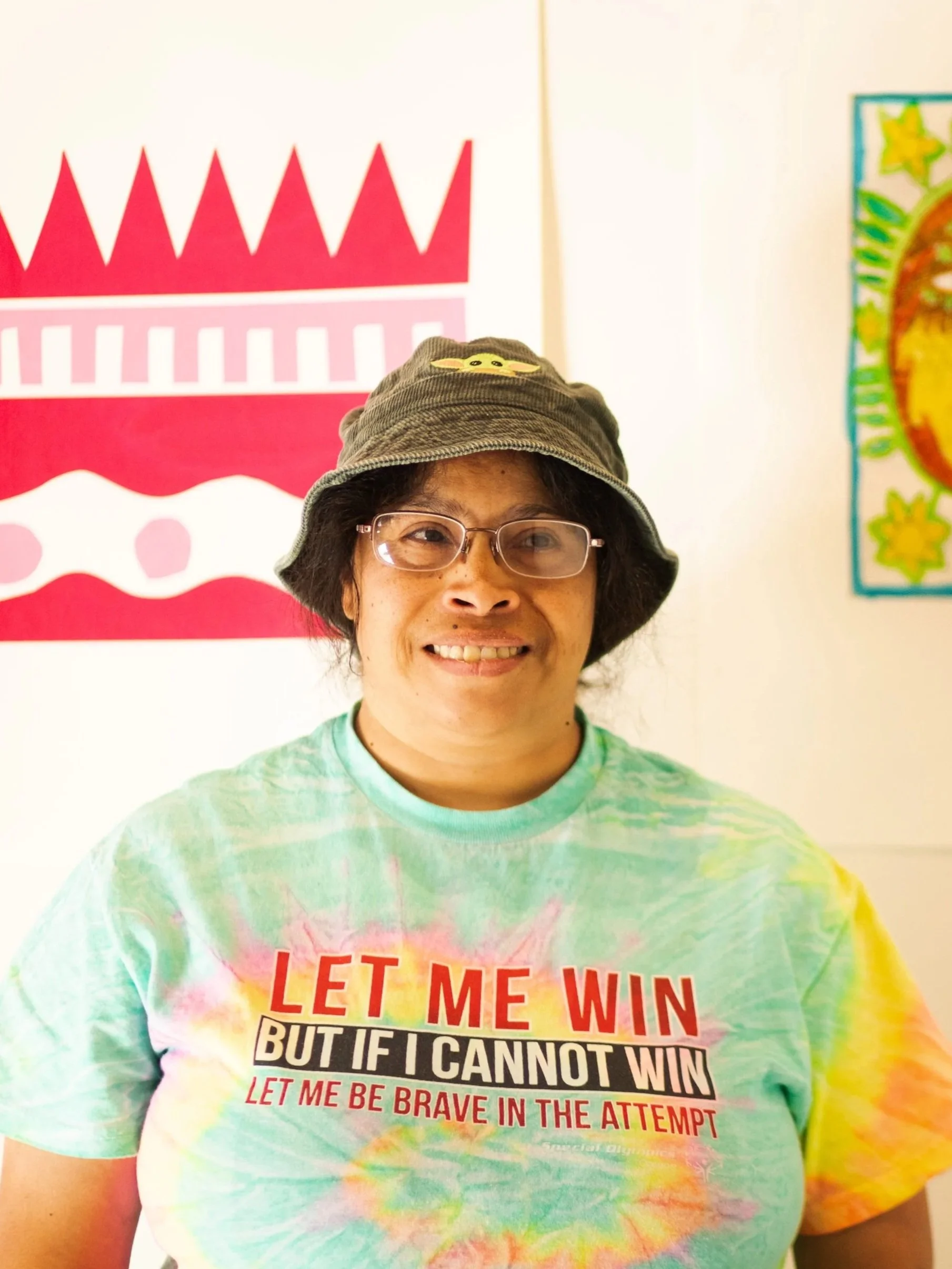Headshot of Artist Annie Rose Macer in front of Artwork