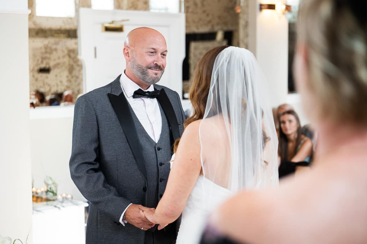groom smiling at bride during wedding ceremony
