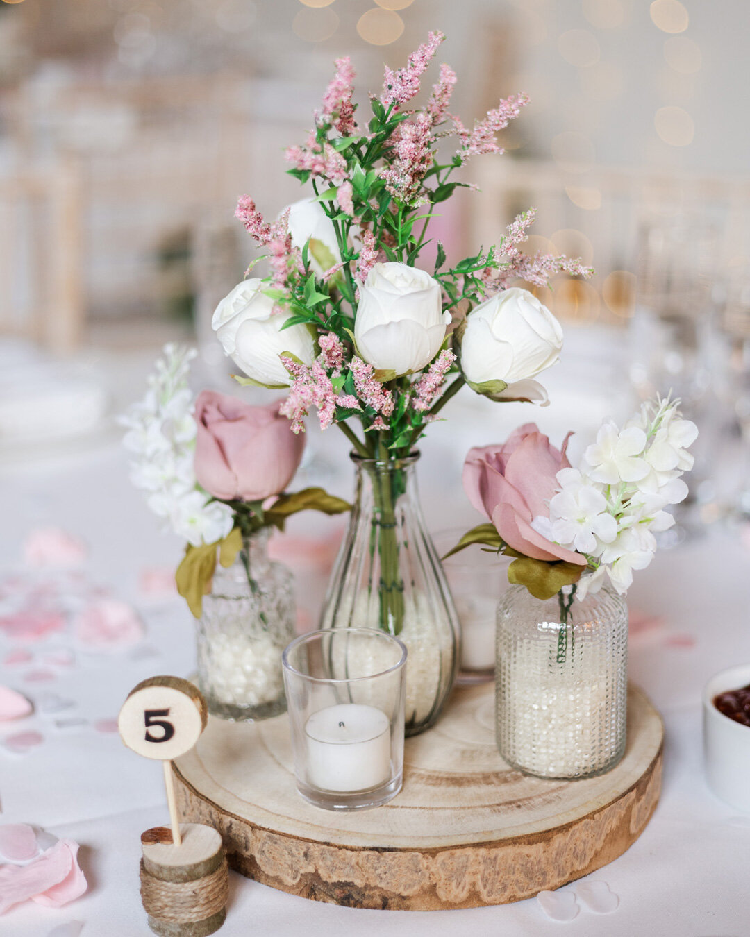 Delicate flowers in little vases have been very popular over the last year as centre pieces. They are easy to make yourself, or have your florist create them and they look so cute! But we also love the hoops that create a statement piece but allows t