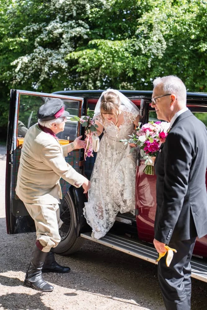 Bride stepping out of wedding car at Layer Marney