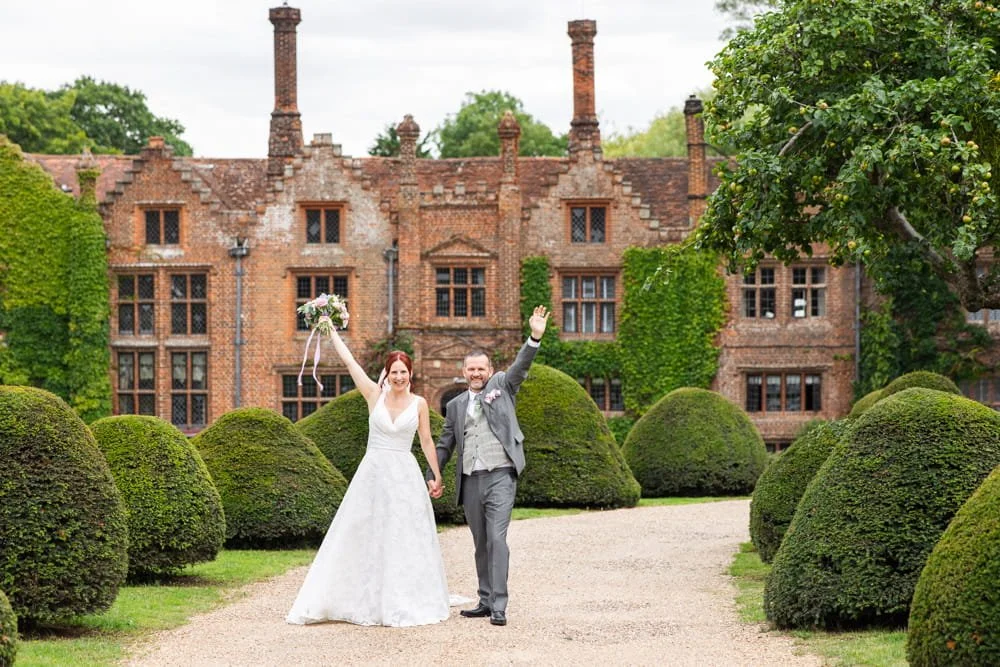 bride and groom cheering outside manor house