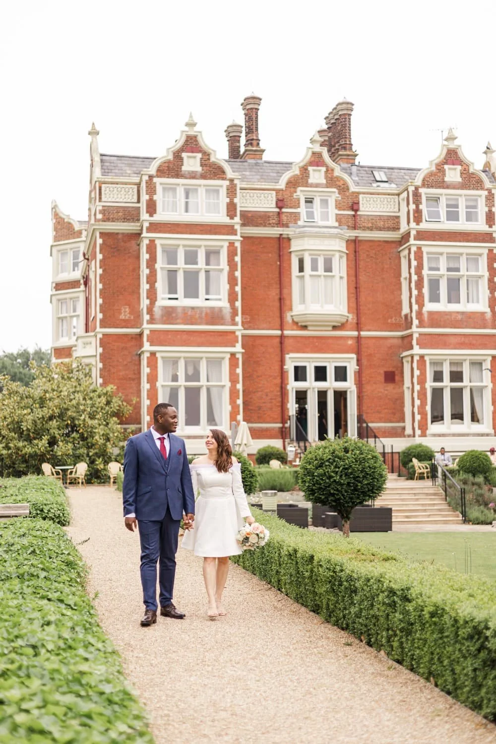 bride and groom walking in front of wivenhoe house