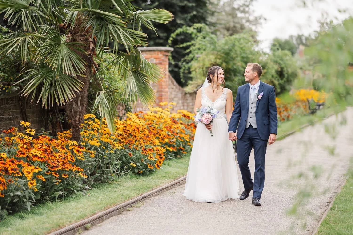bride and groom walking in Colchester Castle Park