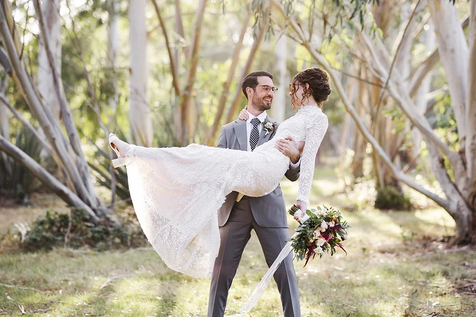 Groom lifting bride, amongst trees at Marks Hall