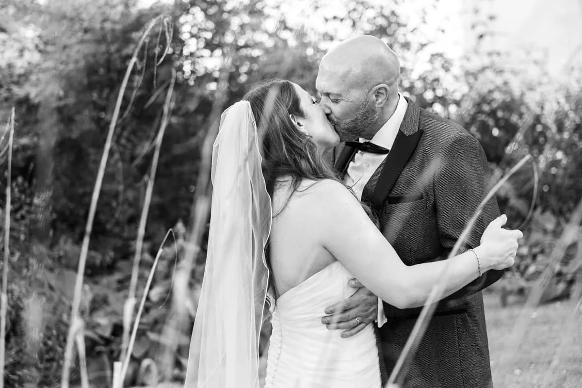 black and white photo of bride and groom kissing
