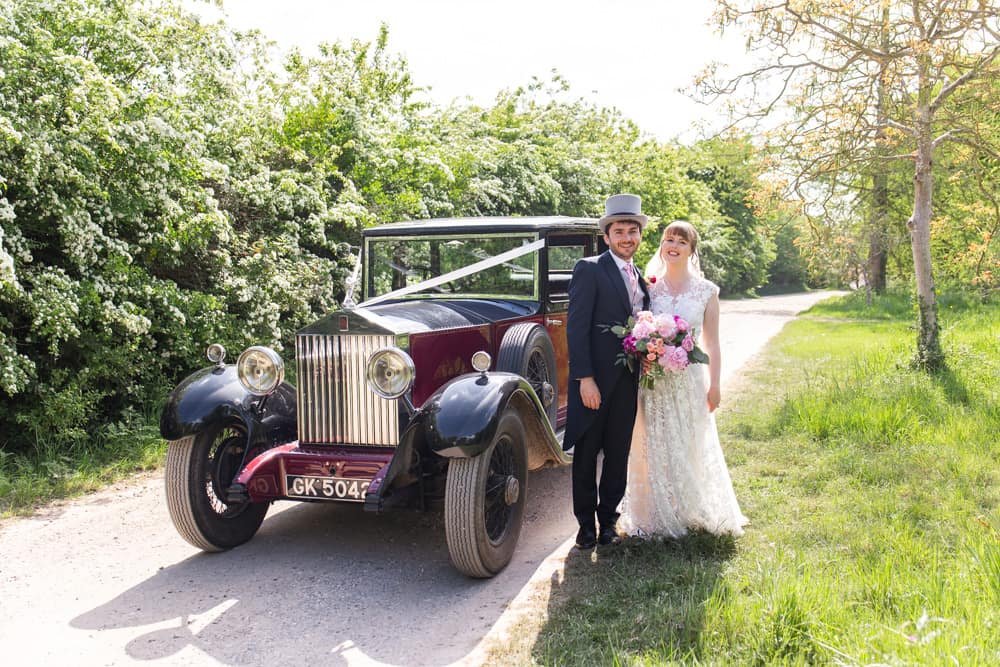 bride and groom standing beside wedding car