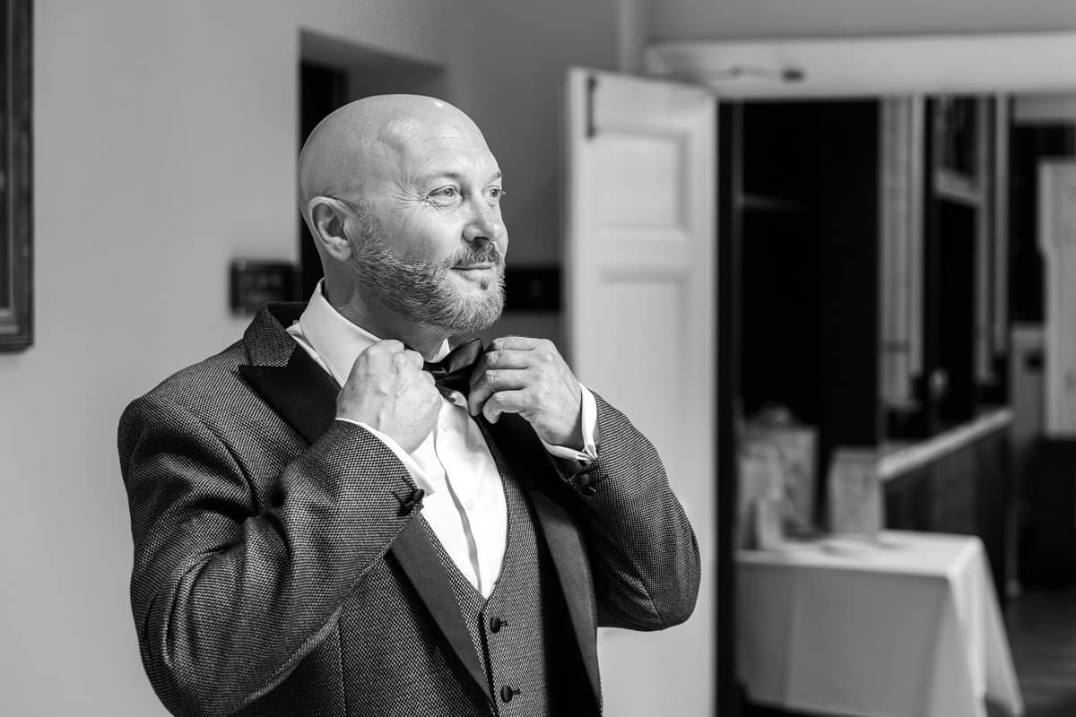 groom fixing his bowtie before the wedding ceremony
