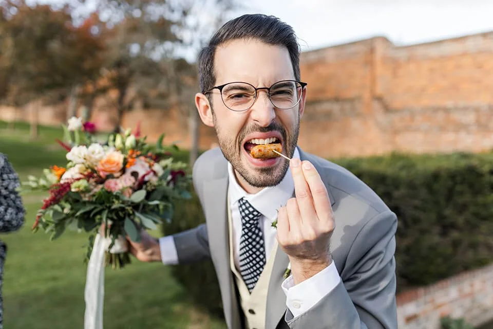 groom eating cocktail sausage at wedding