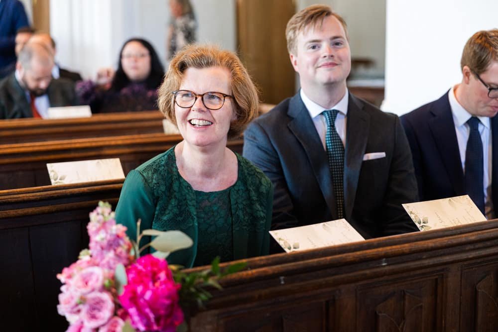 bride's mother sitting in church pew smiling 