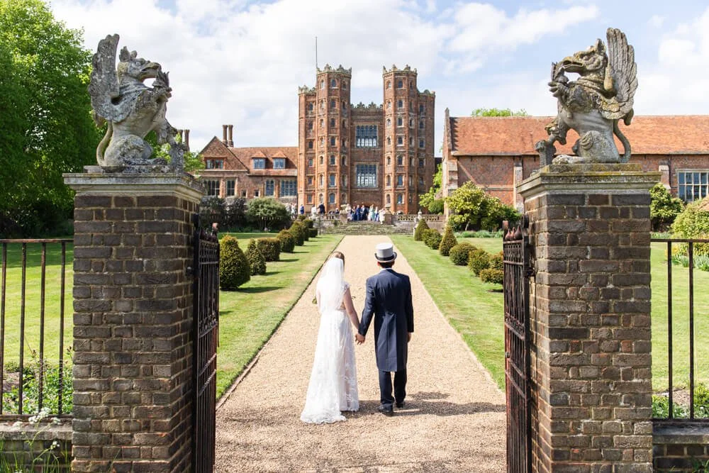bride and groom walking up path towards Towers at Layer Marney
