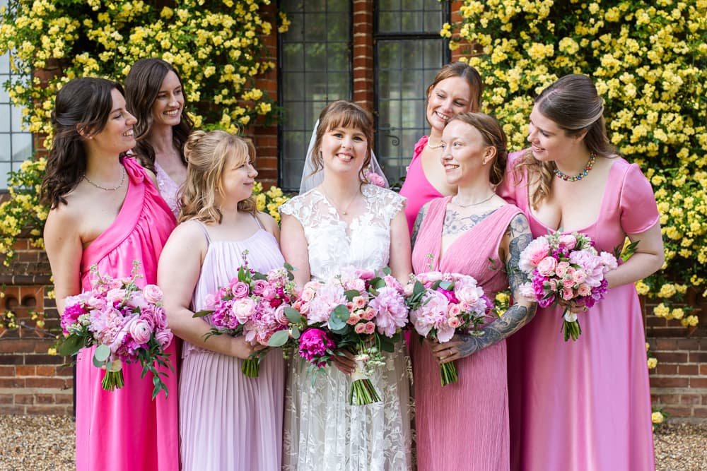 bridesmaids in pink dresses surrounding bride