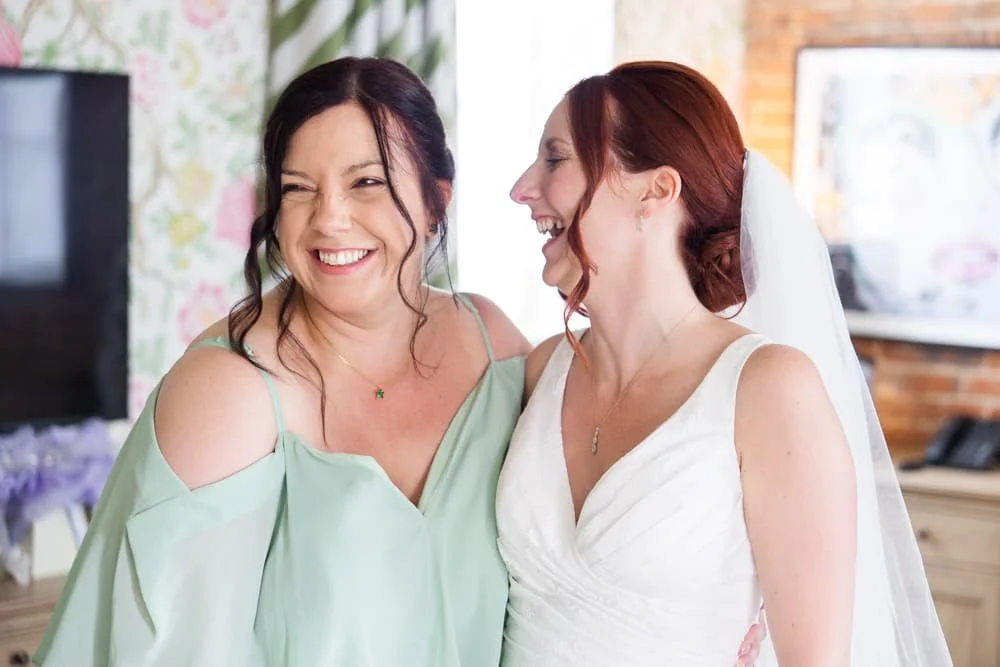 bride and bridesmaid laughing together
