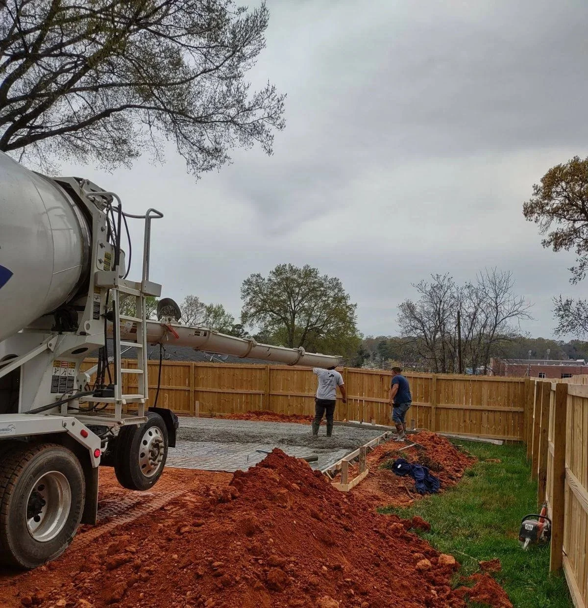 Contractors pouring a concrete slab in a backyard in Mooresville NC