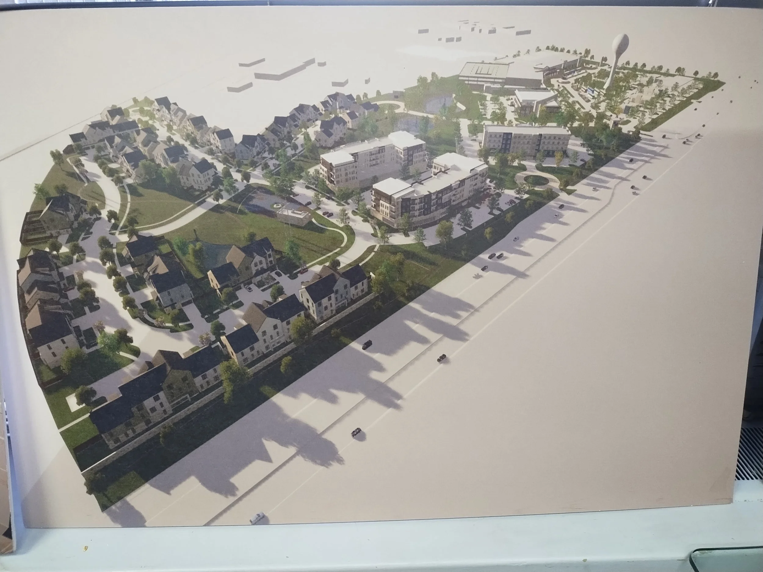 A detailed architectural layout of a residential development, showing houses, buildings, roads, parking areas, and green spaces.