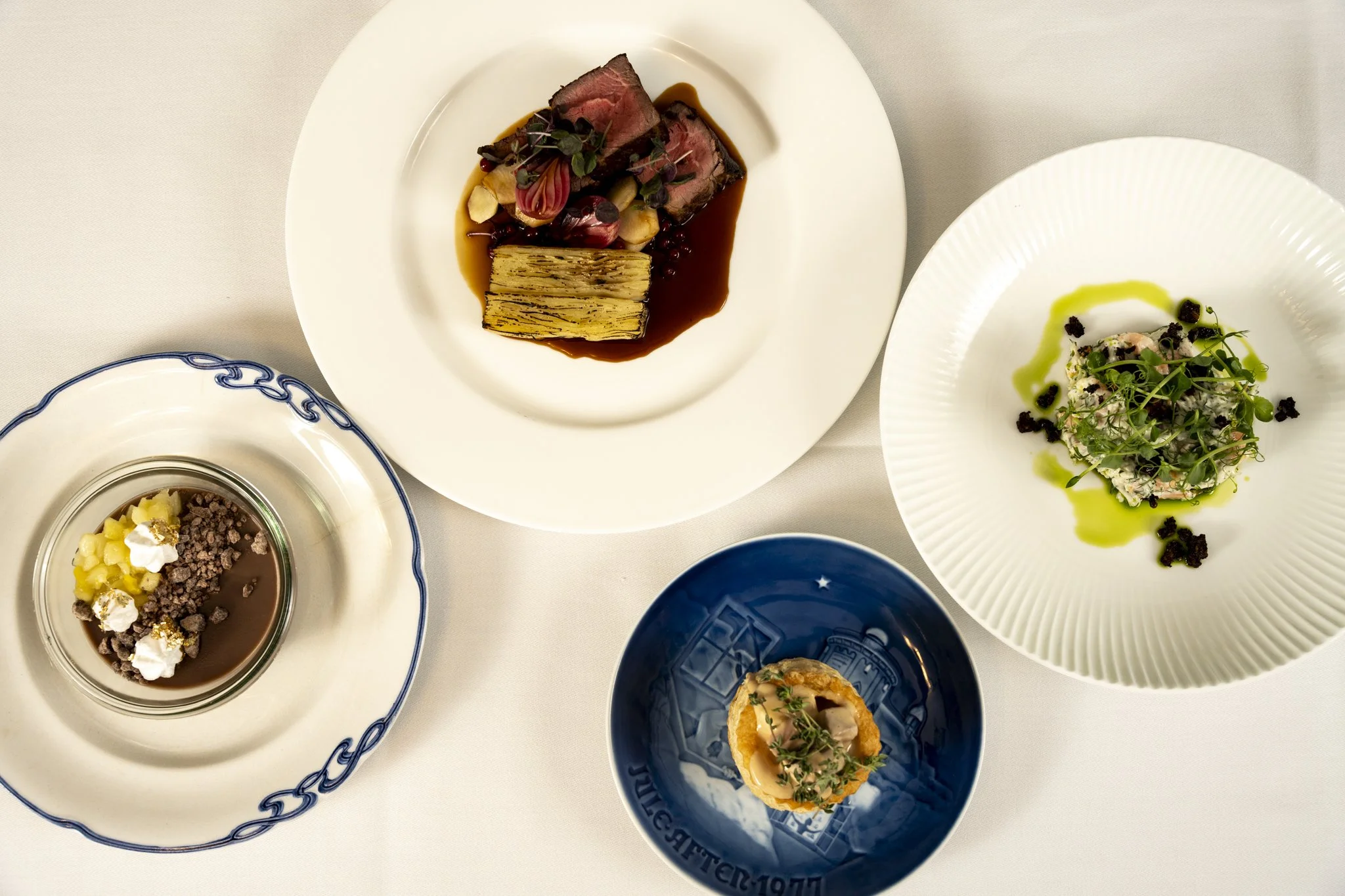 Nytårsmenuen 2024
Forret: “Skagen-salat” med hvid fisk og skaldyr, urteolie og maltknas.
Mellemret: Vol au vent med lokal vildtskudt fasan fra Clausholm slot.
Hovedret: Sashi-okse med Pommes Anna, samt sauce bordelaise og tyttebær.
Dessert: Bistrotek