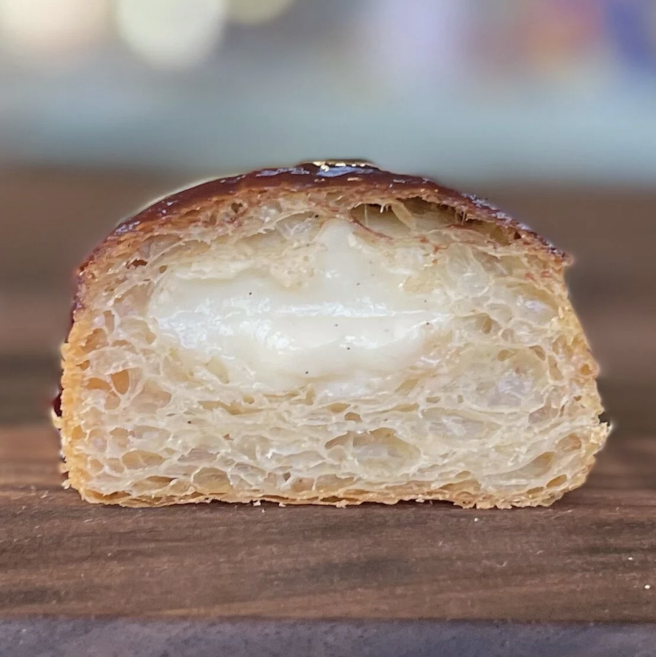 Close-up of a slice of cream-filled croissant on a wooden surface.