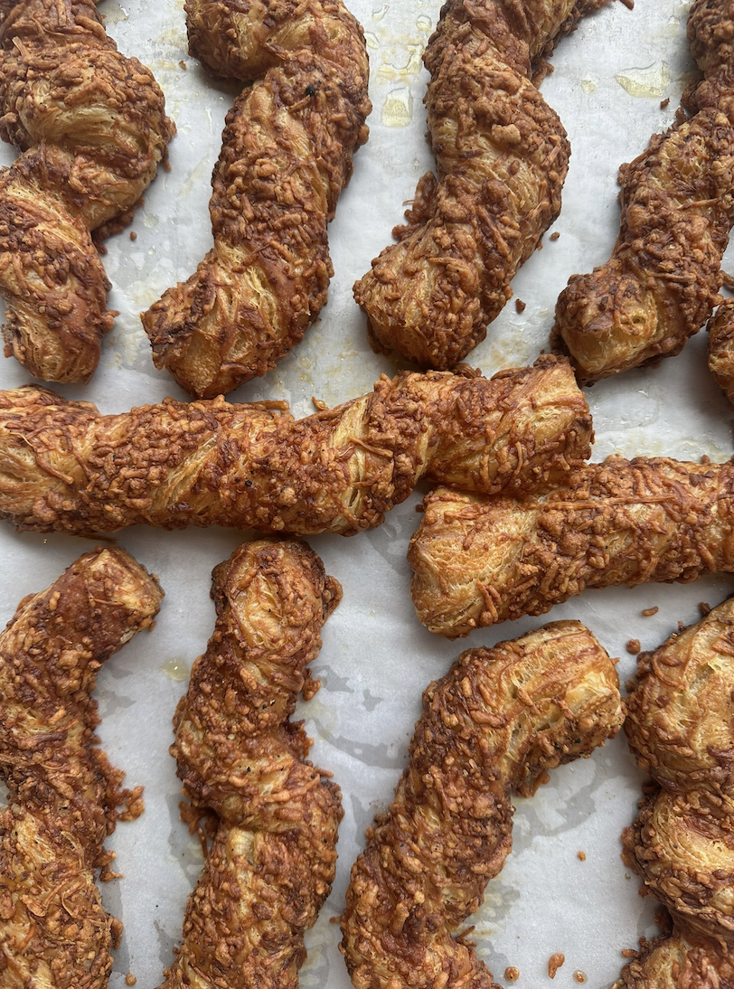 Close-up of multiple pieces of fried chicken drumsticks coated with a crunchy, crispy breading on a baking sheet covered with parchment paper.